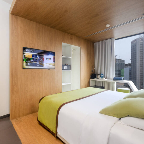 a hotel room with a bed and a television on the wall