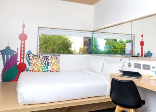 a hotel room with a bed a desk and a laptop