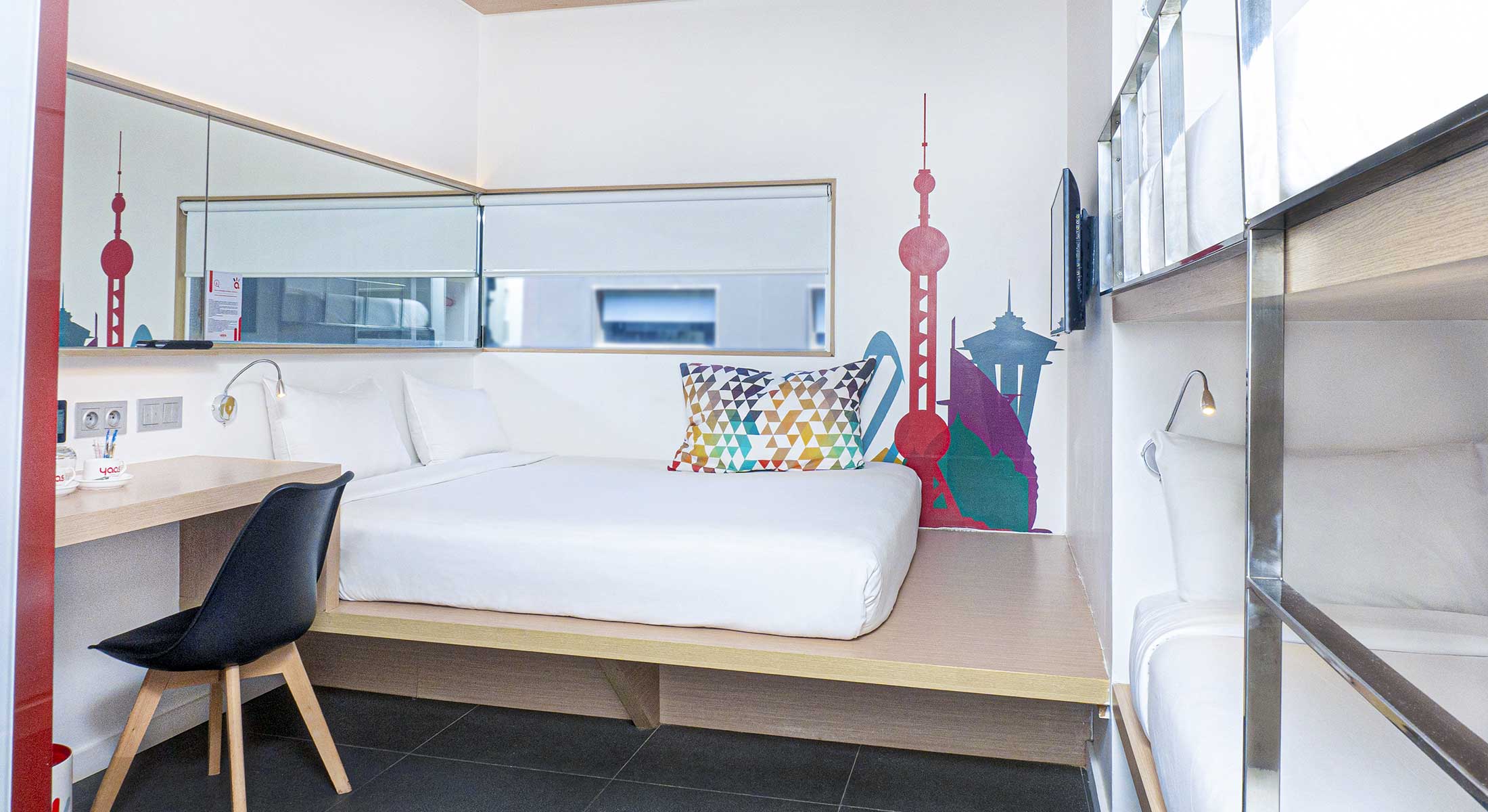 a small hotel room with a bed and a desk