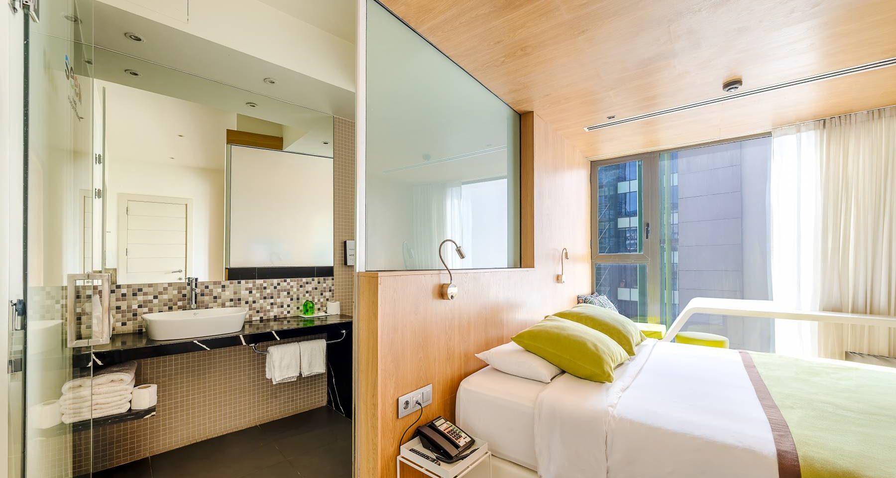 Chambre d'hôtel moderne comprenant un lit et une salle de bains ouverte sur la chambre.