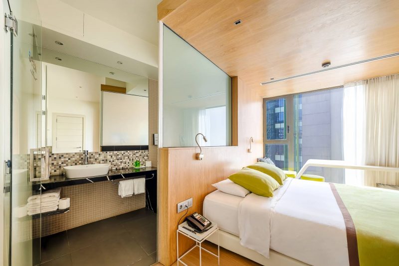 Chambre d'hôtel moderne comprenant un lit et une salle de bains ouverte sur la chambre.