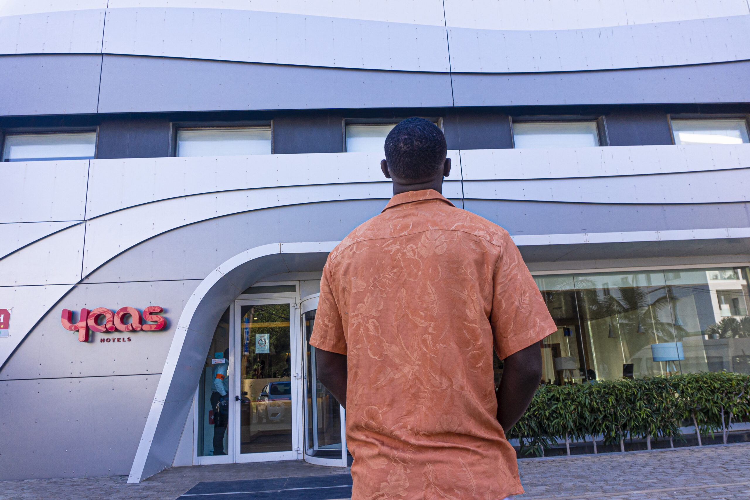 a man stands in front of a yaas hotel