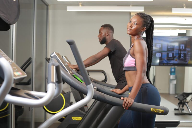 un homme et une femme marchent sur un tapis roulant dans une salle de sport