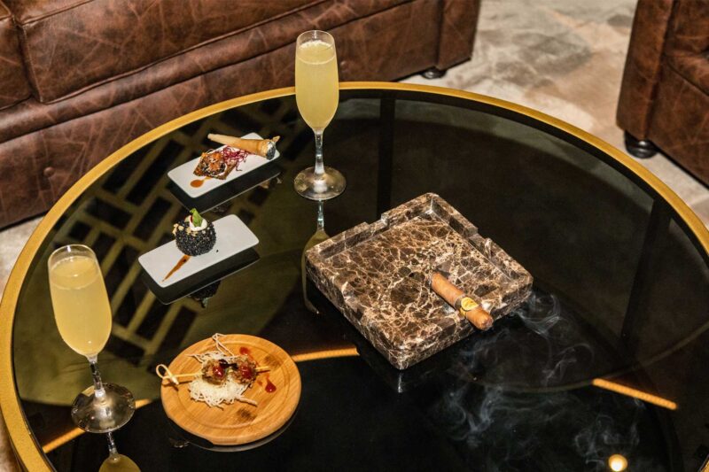 une table avec un cigare et deux verres de champagne