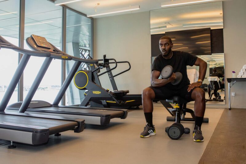 un homme assis sur un banc tenant un haltère dans une salle de sport