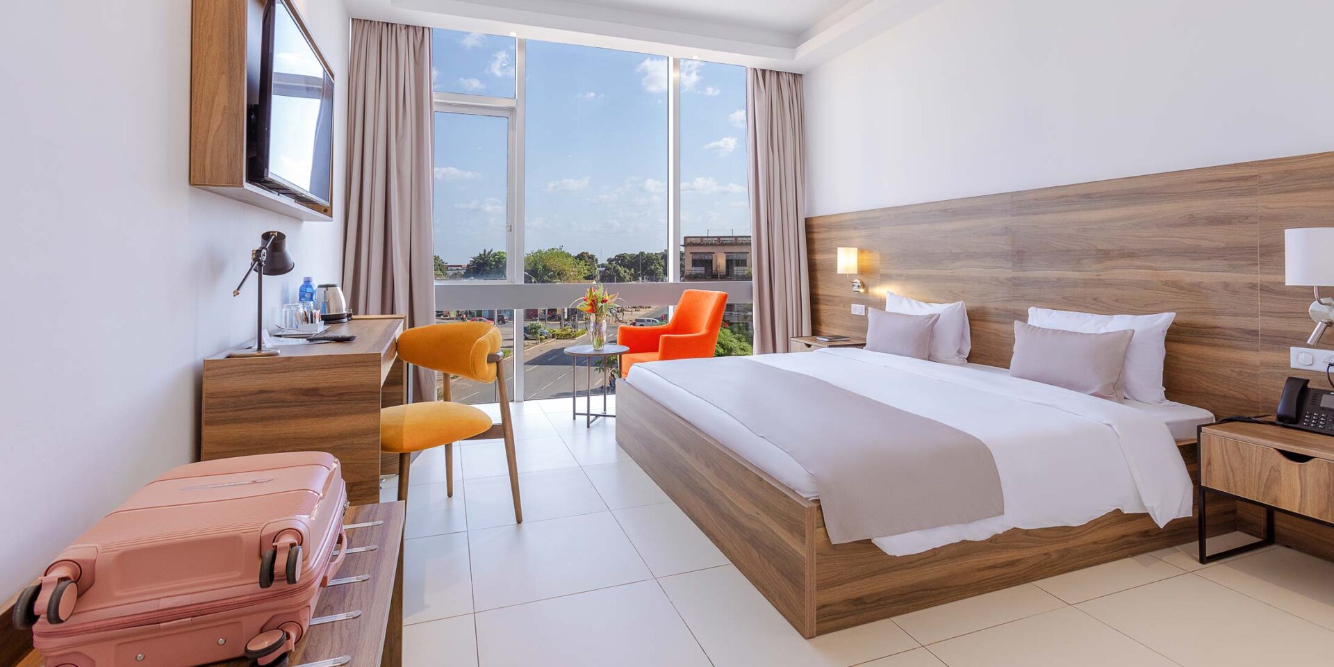 a hotel room with a large bed and a pink suitcase