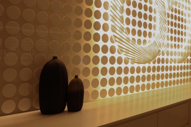 two vases sit on a counter in front of a wall with circles on it
