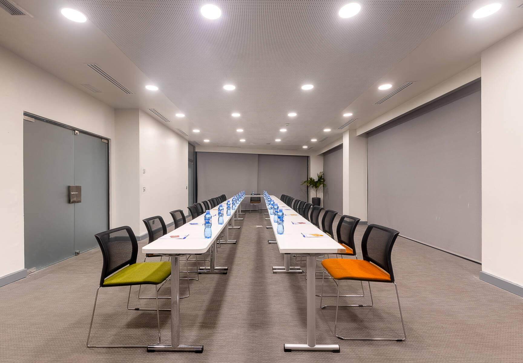 une salle de conférence avec des tables et des chaises et un écran avec le logo