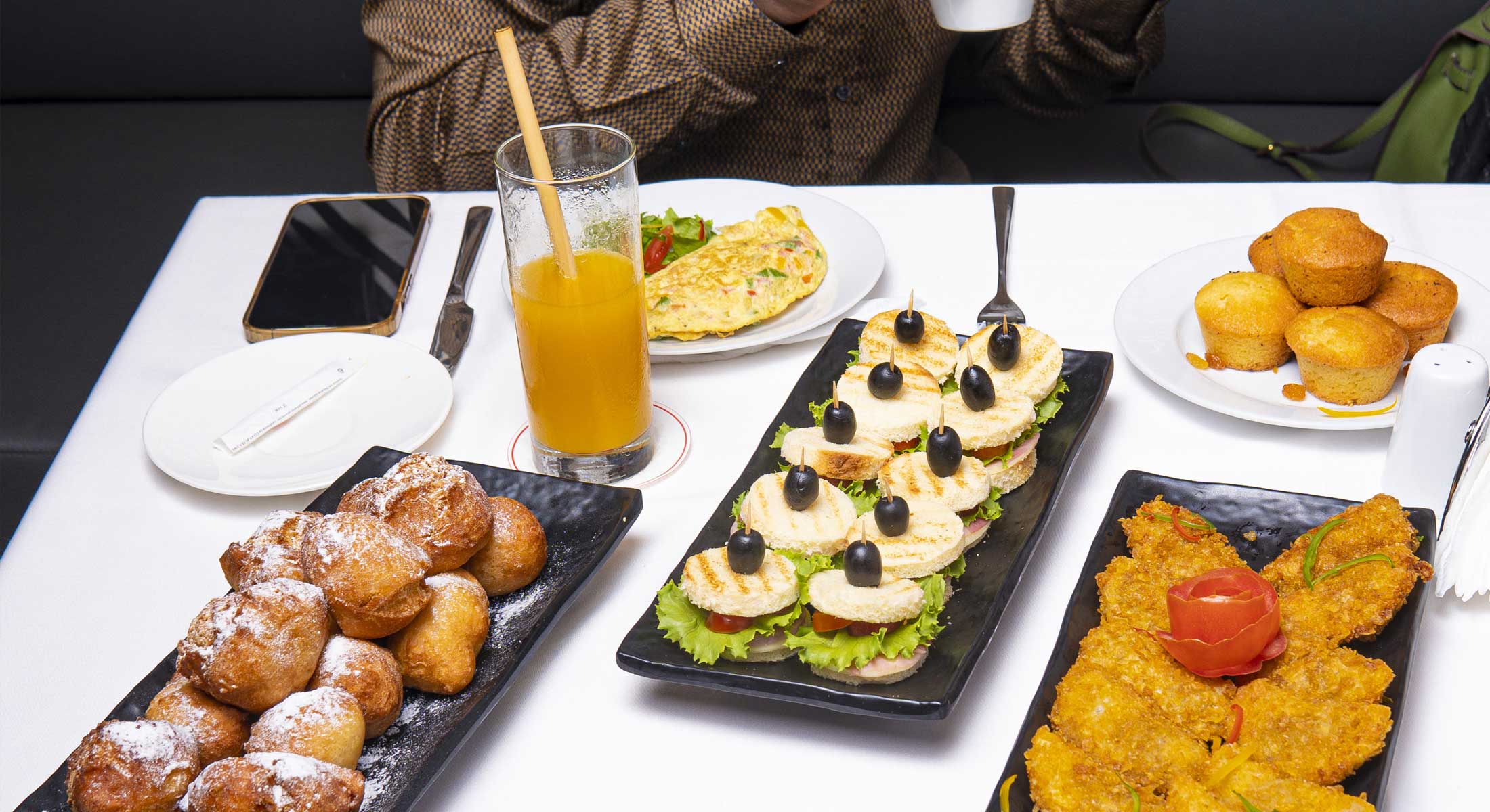 a table with plates of food and a glass of orange juice
