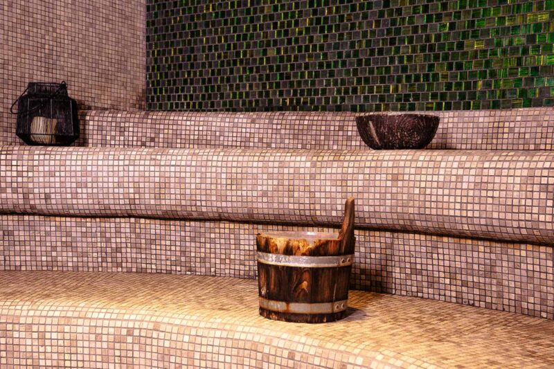 un seau en bois est assis sur les marches d' un sauna