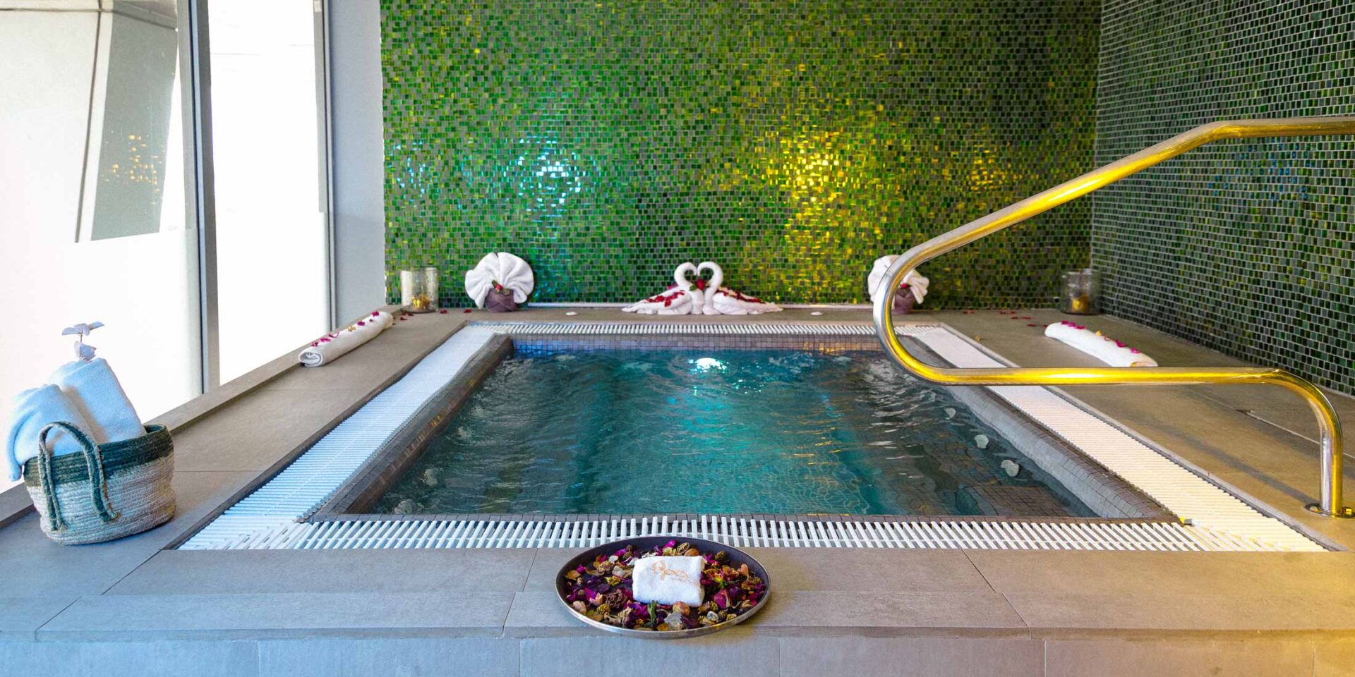 un bain à remous dans un spa avec un mur en mosaïque verte