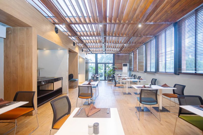 Salle de restaurant moderne avec des tables dressées et un plafond à lattes de bois.
