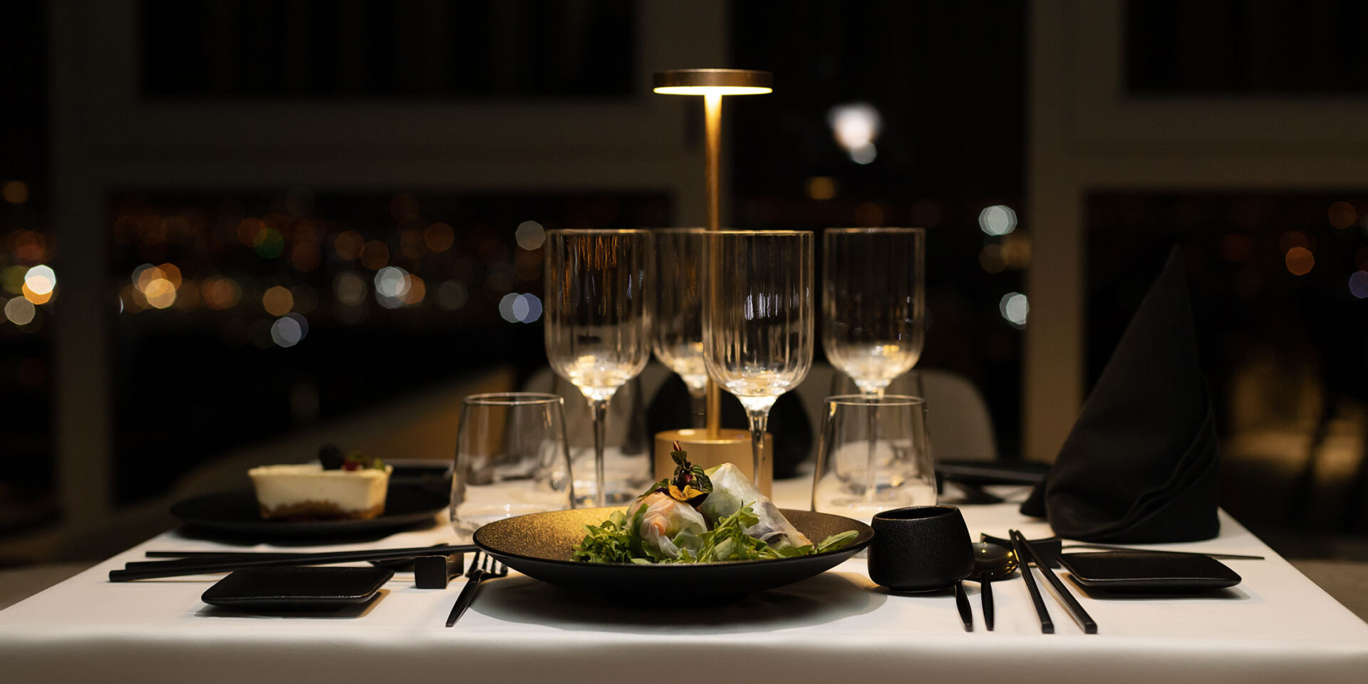 une table avec une assiette de nourriture et des verres de vin