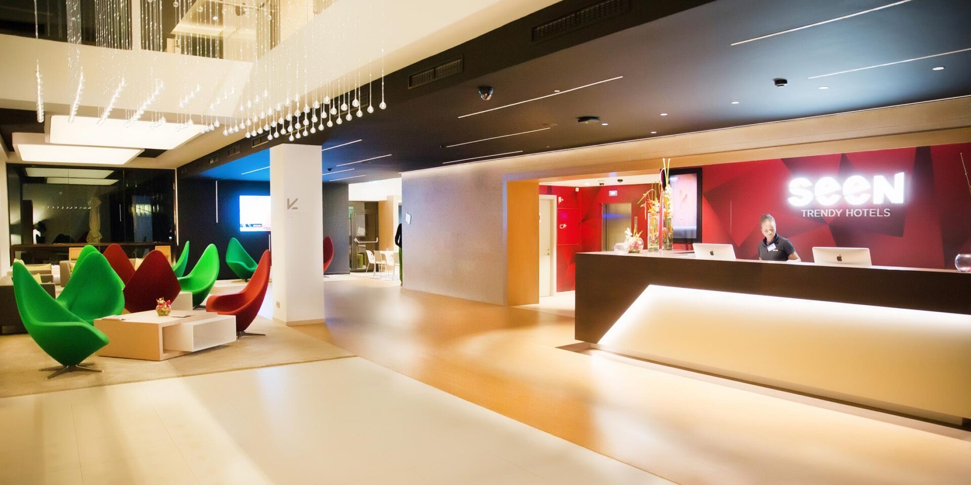 a reception desk for seen trendy hotels with a man behind it