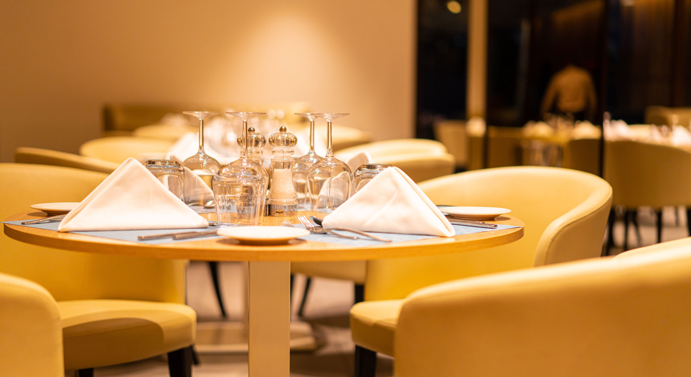a table in a restaurant with glasses and napkins on it