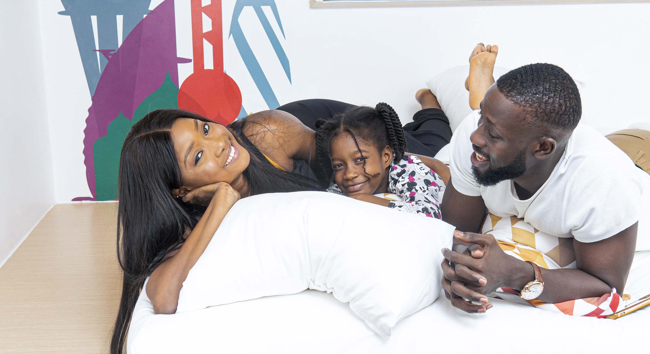 a man and a woman lying on a bed with a little girl