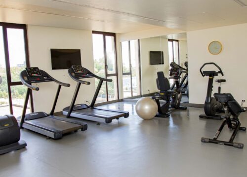 a gym with treadmills exercise bikes and a clock on the wall
