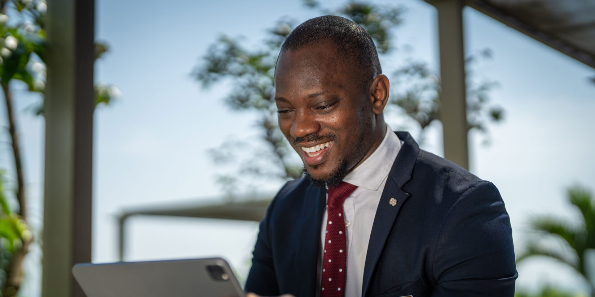 a man in a suit and tie is smiling while looking at a tablet