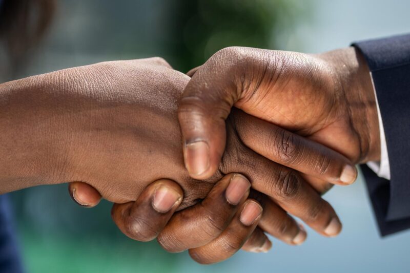 two people shaking hands with one wearing a blue jacket