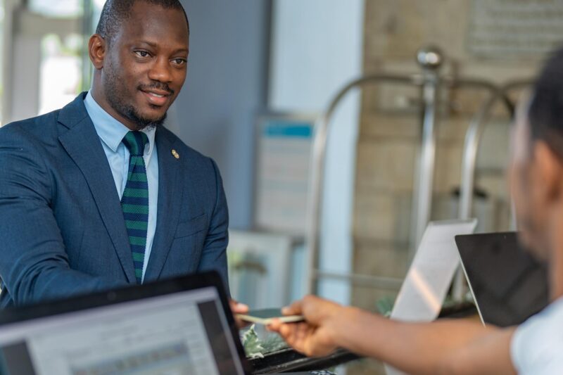 a man in a suit and tie is giving a credit card to another man