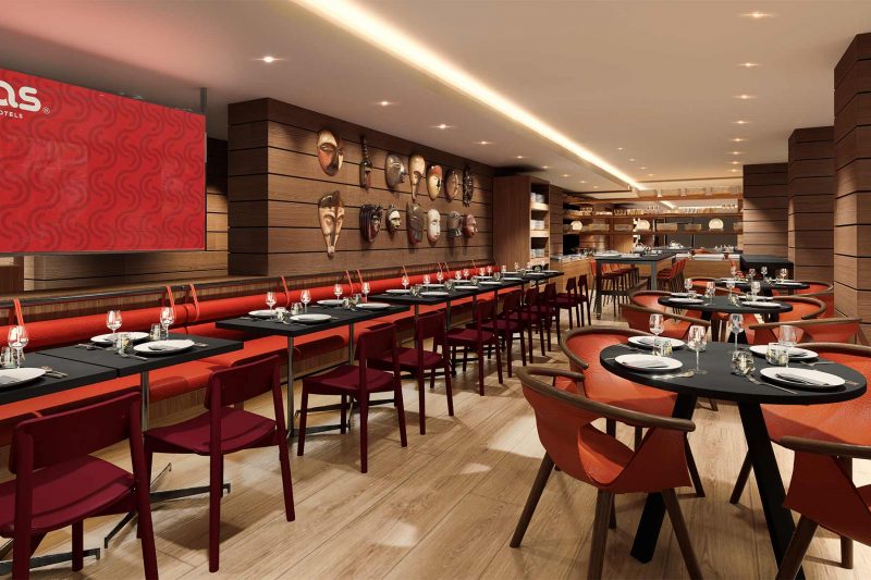 Modern hotel restaurant with red chairs, tables, and African masks on wooden walls.