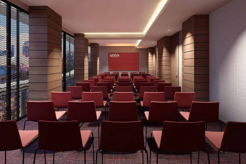 Conference room with rows of red chairs facing a presentation screen.