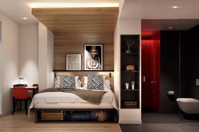 Modern hotel room with a wood-paneled bed alcove and an adjoining bathroom.