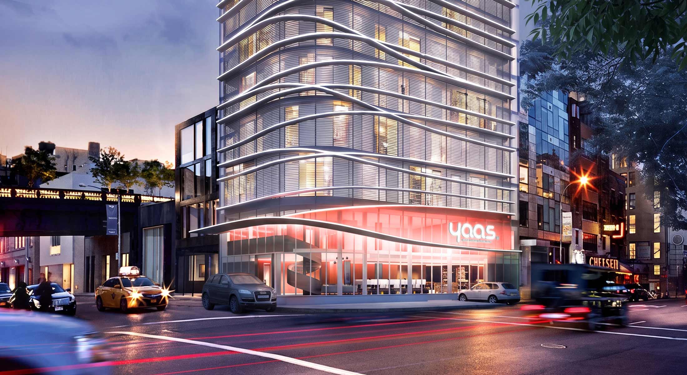 Modern hotel with undulating facade at a city street intersection at night.